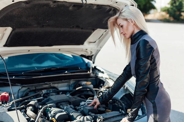 Beautiful female blonde mechanic repairs car engine — Stock Photo, Image