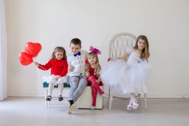 Çocukların doğum günü arkadaşları tatilde kırmızı balonlarla otururlar.