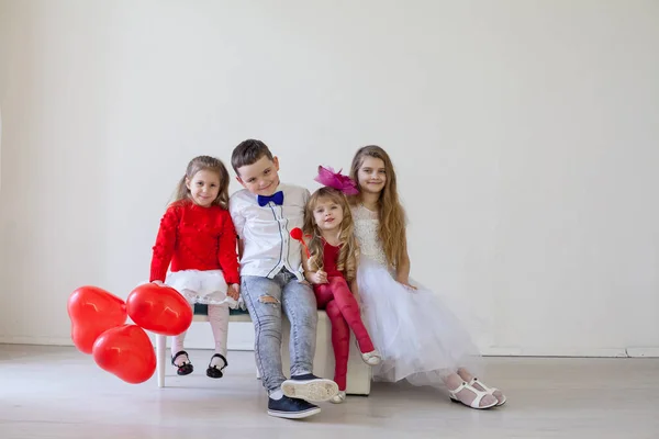 Niños amigos se sientan con globos rojos en el cumpleaños de vacaciones — Foto de Stock