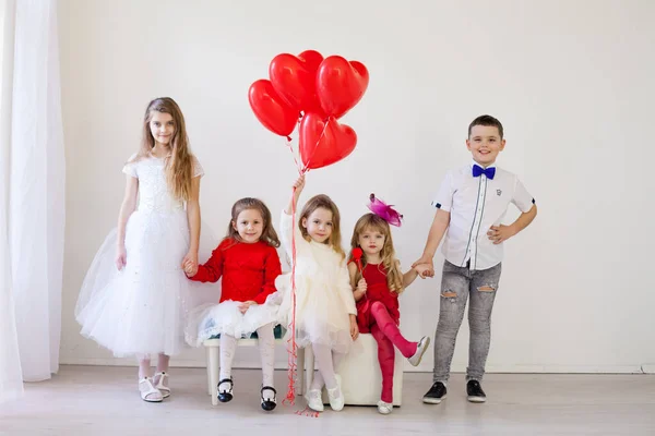 Amici per bambini si siedono con palloncini rossi per il compleanno delle vacanze — Foto Stock