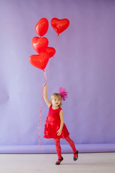 Bella bambina che tiene palloncini rossi per la vacanza — Foto Stock