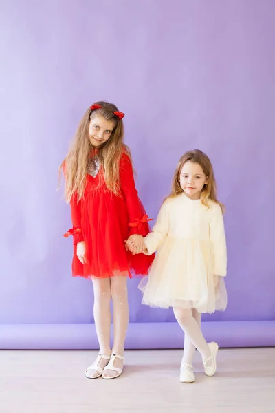 Due bambine in abito rosso e bianco si tengono per mano — Foto Stock