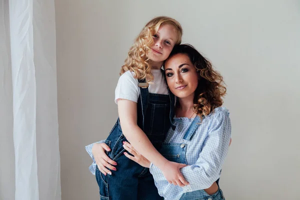 Moeder brunette en dochter blond in jeans zitten op de vloer — Stockfoto