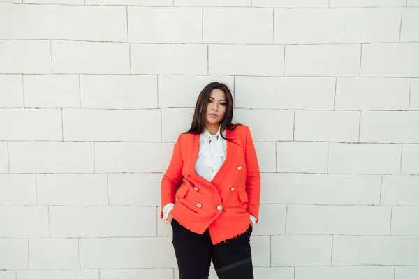 Hermosa mujer morena en chaqueta roja se encuentra en la pared blanca —  Fotos de Stock