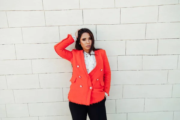 Hermosa mujer morena en chaqueta roja se encuentra en la pared blanca — Foto de Stock