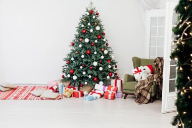 Beyaz odanın yeni yıl kartı, kırmızı dekor ve hediyeli Noel ağacı.