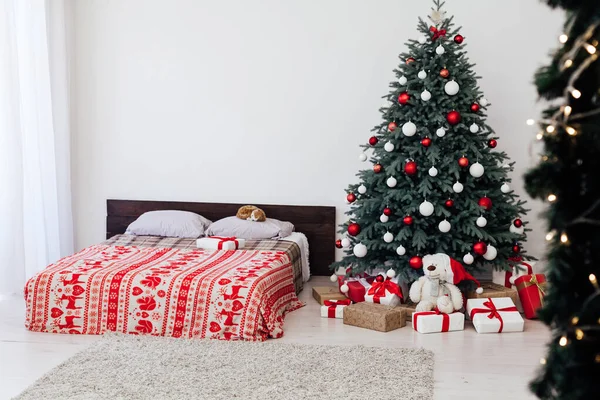Interior do quarto da véspera de Ano Novo com cama de decoração vermelha e árvore de Natal com presentes — Fotografia de Stock