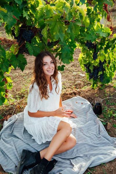 Vacker kvinna i klänning med ett glas vin på en picknick i vingården — Stockfoto