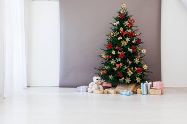 Yeni yıl hediyeleriyle Noel ağacı çamı. Bayram için kırmızı dekorasyon, gri arka plan.