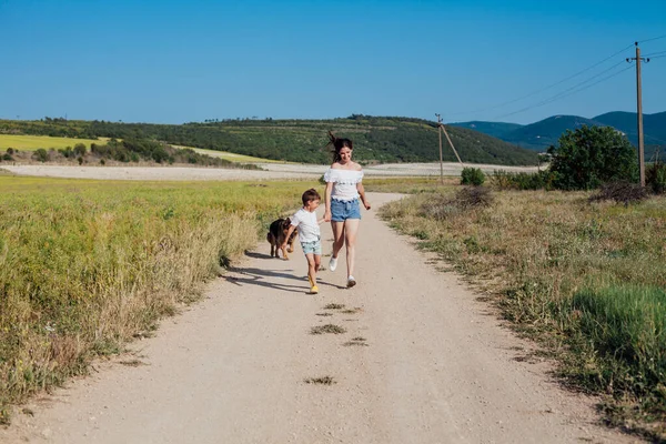 Mãe e filho caminham com o cão a caminho do campo — Fotografia de Stock
