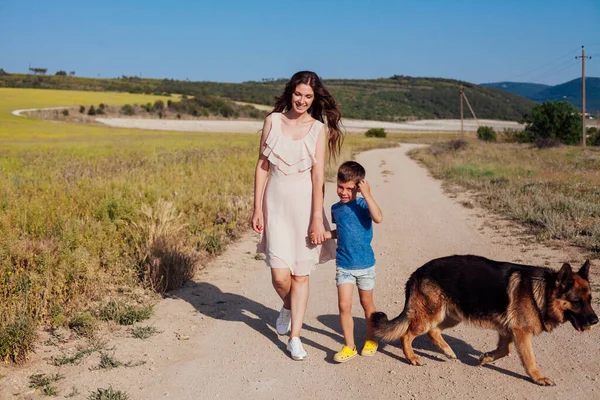 Maman et son fils marchent avec le chien sur le chemin du champ — Photo