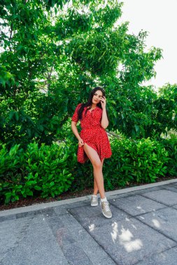Kırmızı puantiyeli güzel esmer kadın. Sokakta benekli elbise.