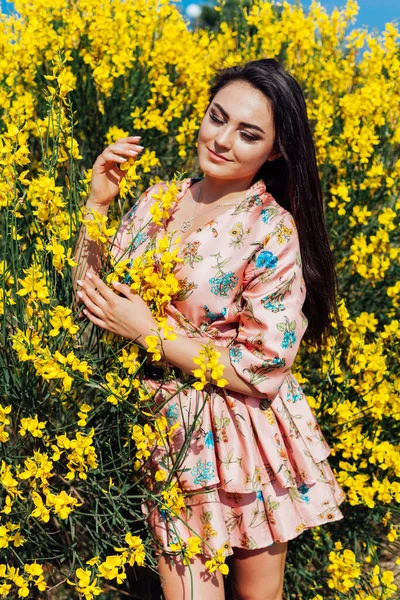 Schöne brünette Frau in einem Kleid mit Blumen spaziert allein durch den Park — Stockfoto