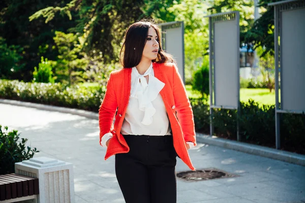 Красива бізнес-леді брюнетка в червоній куртці на прогулянці на вулиці — стокове фото