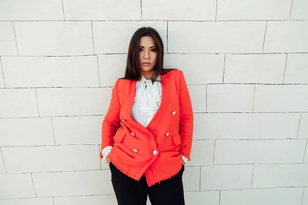 Beautiful fashion business woman brunette in a red jacket on a walk in the street — Stock Photo, Image