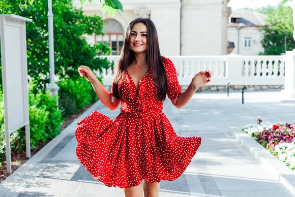 Kırmızı elbiseli, puantiyeli güzel esmer kadın sokakta yürüyor. — Stok fotoğraf