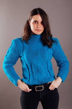 Mavi kışlık süveter giyen, şık, esmer bir kadının portresi.