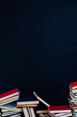 Eğitim için kütüphanede siyah arkaplan üzerine yazılmış kitap yığınları