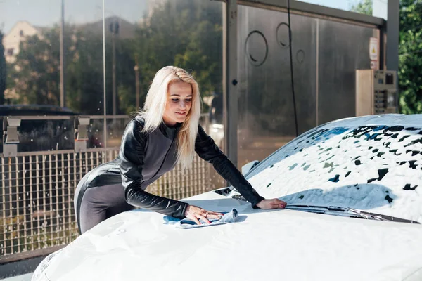 Hermosa mujer rubia lava la espuma blanca del coche en el lavado de coches — Foto de Stock