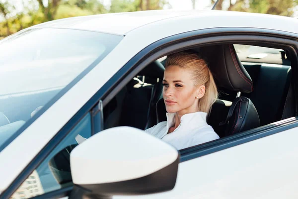 Hermosa mujer rubia en la carretera conduciendo un coche blanco — Foto de Stock