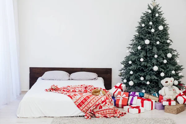 Nieuwjaar slaapkamer decor met kerstboom bed met geschenken en slingers interieur — Stockfoto