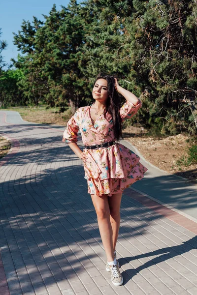 Schöne Frau in einem Kleid mit Blumen spaziert allein durch den Park — Stockfoto