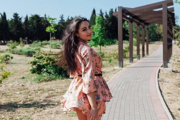 Beautiful woman in a dress with flowers walks in the park alone — Stock Photo, Image