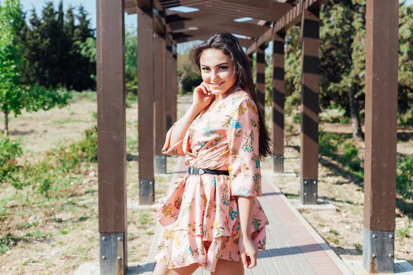 Mulher bonita em um vestido com flores caminha no parque sozinho — Fotografia de Stock