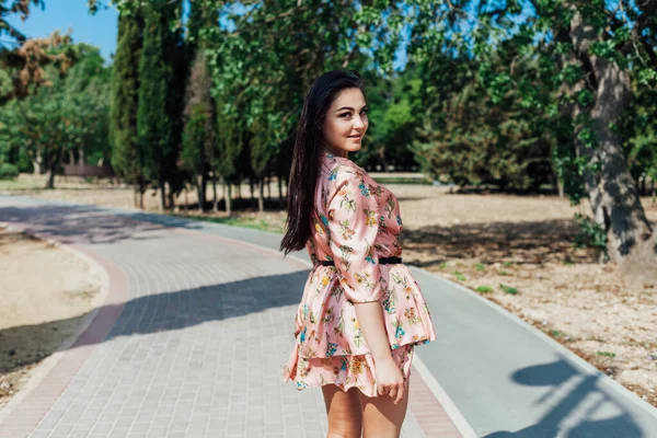 Piękna kobieta w sukience z kwiatami spaceruje samotnie po parku — Zdjęcie stockowe