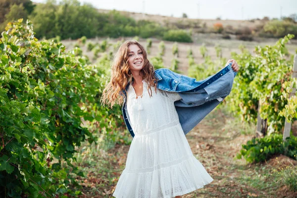 Bela mulher em vestido branco e jaqueta de ganga nas vinhas — Fotografia de Stock