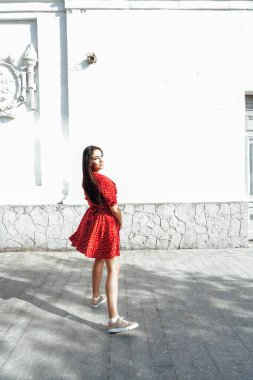 Kırmızı elbiseli güzel esmer kadın şehrin sokaklarında yürüyor.