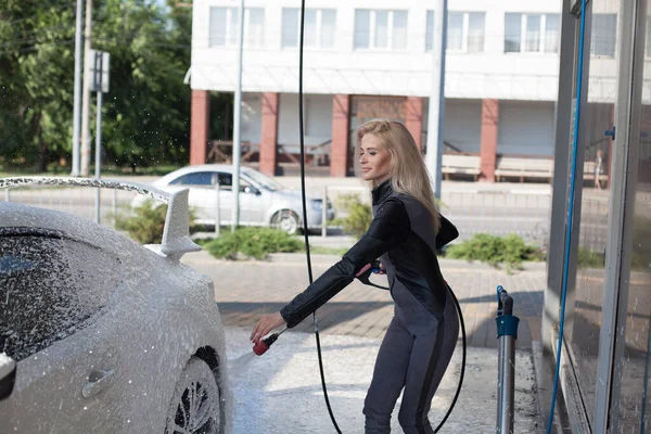 female blonde driver washes car at car wash