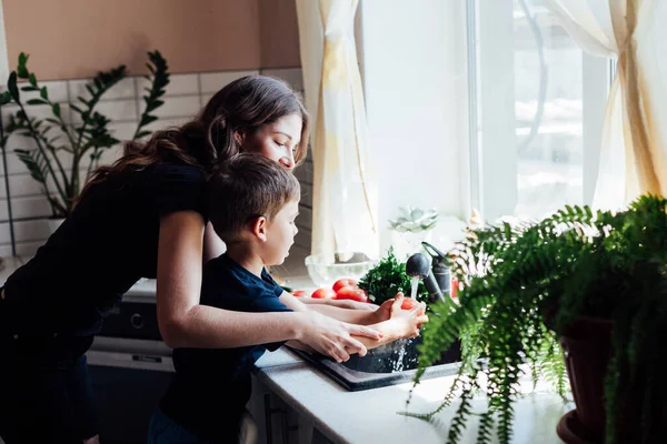 Мама з сином миє овочі на кухні — стокове фото