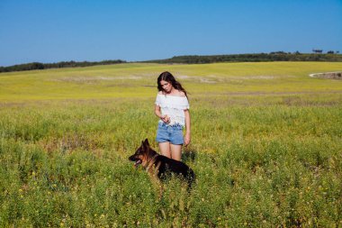 Güzel bir kadın köpeğiyle birlikte tarlada yürüyor.