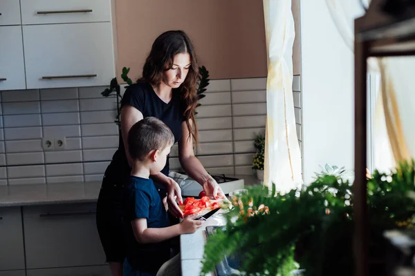 Mom and young son cut vegetables for salad in the kitchen — Stock Photo, Image
