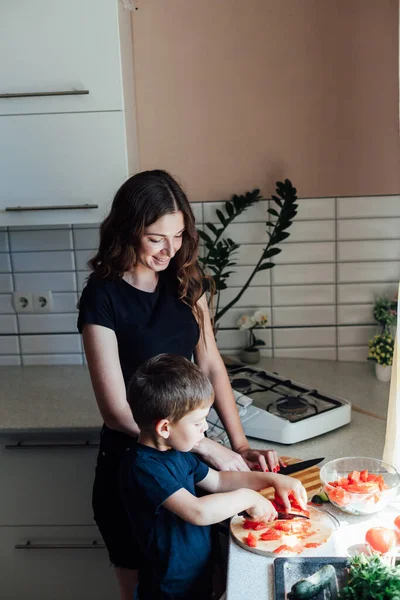 Mutter und kleiner Sohn schneiden Gemüse für Salat in der Küche — Stockfoto