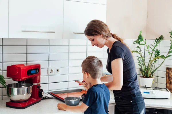 Жінка і син готують солодкі торти на кухні — стокове фото