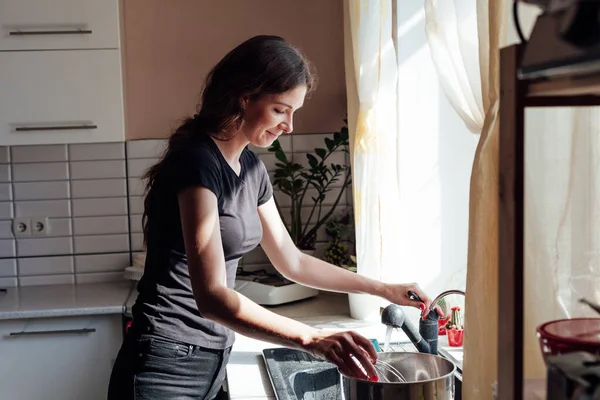 woman washes dirty dishes in the kitchen