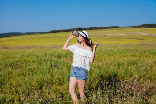 Retrato de uma bela mulher na moda em um chapéu em um campo sozinho — Fotografia de Stock
