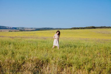 Elbiseli güzel bir kadın sahada mutlu bir şekilde yürüyor.