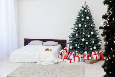 Yeni yıl yatak odası dekoru, içinde hediyeler ve çelenkler olan Noel ağacı yatağı.