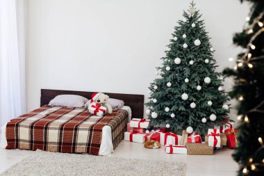 Yeni yıl yatak odası dekoru, içinde hediyeler ve çelenkler olan Noel ağacı yatağı.
