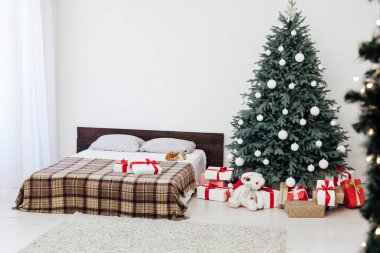 Yeni yıl yatak odası dekoru, içinde hediyeler ve çelenkler olan Noel ağacı yatağı.