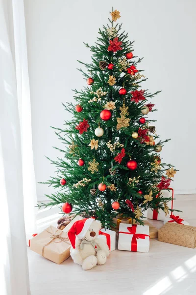 一棵美丽的大圣诞树，装饰着美丽的闪光的灌木，木地板上有许多不同的礼物. — 图库照片