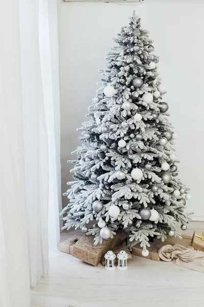 Interni domestici. Una stanza con un bellissimo albero di Natale innevato e regali sotto questo albero. — Foto Stock