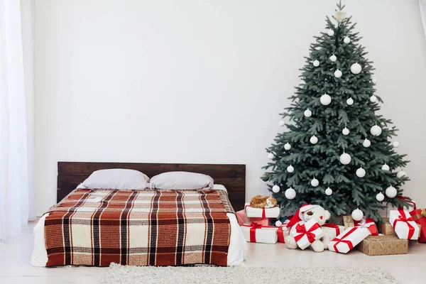 Kerstboom met geschenken in de slaapkamer bed bloemenslingers het nieuwe jaar interieur — Stockfoto