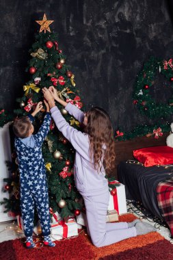 Anne ve çocuk Noel ağacını süslüyor Yeni yılda