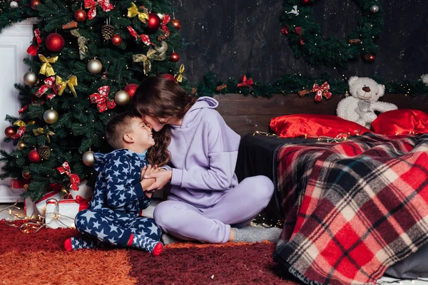 Мама и мальчик открывают подарки на новогоднюю елку — стоковое фото