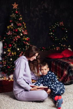 Noel ağacı ışıklarında anne ve oğul yeni yıl hediyeleri.