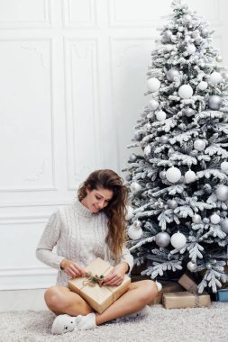 Güzel bir kadın yılbaşı ağacı hediyelerini açar.